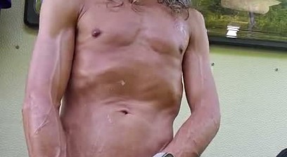 Skinny boy nourishes his skin after showering with cream and oil. The neighbors next door can watch
